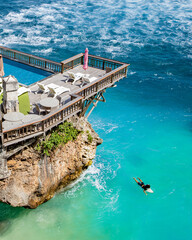 Perched atop rugged cliffs, a swimming pool overlooks the turquoise waters of Blue Point Beach in...