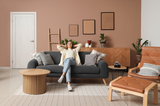 Young pretty woman resting on sofa in beige living room