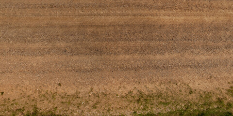 view from above on texture of dry muddy road with tractor tire tracks in countryside