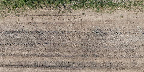 view from above on texture of dry muddy road with tractor tire tracks in countryside