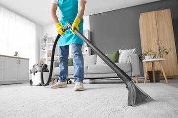 Male janitor cleaning carpet in room