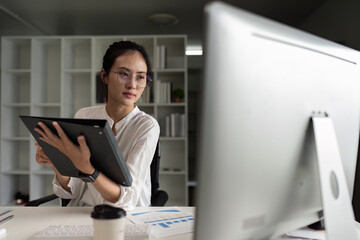 A woman is sitting at a desk with a computer monitor in front of her