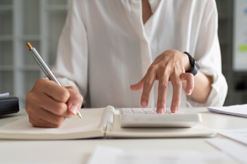 Businesswoman using a calculator to calculate numbers on a company's financial documents, she is analyzing historical financial data to plan how to grow the company. Financial concept