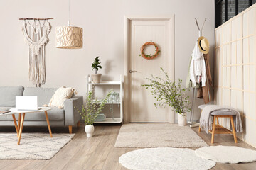 Comfortable sofa, coffee table and vase with blossoming branches in living room
