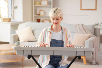 Young woman with short hair playing synthesizer at home