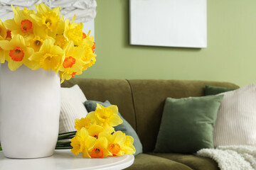 Vase with yellow daffodils on table in living room, closeup