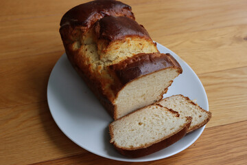 Homemade baked and sliced  Brioche Bread on a white plate on wooden table
