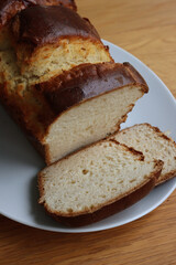 Homemade baked and sliced  Brioche Bread on a white plate on wooden table