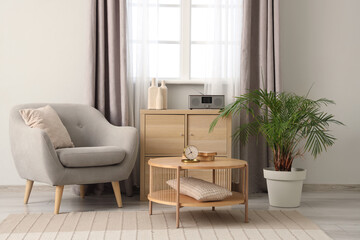 Interior of cozy living room with grey armchair and coffee table near window