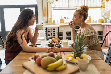 Two Young Women Sharing Laughs and Healthy Breakfast in a Sunny Kitchen
