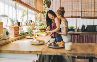 Two Young Women Enjoying a Collaborative Breakfast Preparation in a Sunlit Kitchen