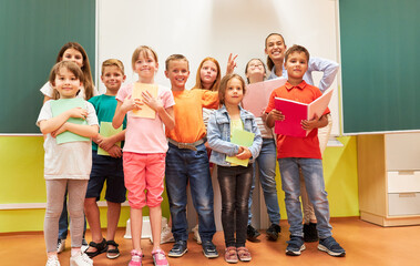 Happy school kids posing with teacher in class