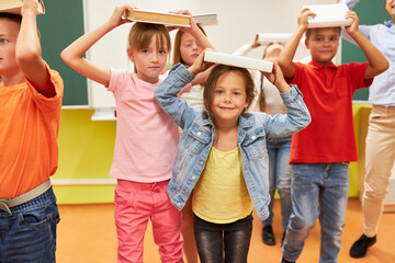 Schoolkids balancing books on head in class