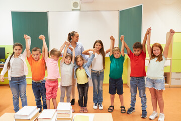 Cheerful schoolkids standing with teacher in class