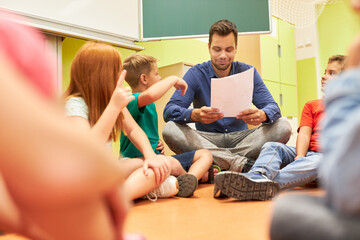Teacher holding paper and sitting with students