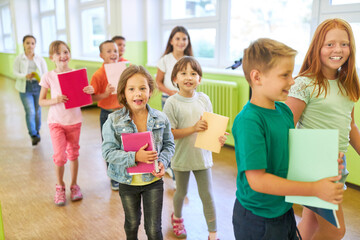 Kids holding books while walking in school hallway