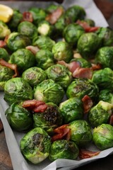 Delicious roasted Brussels sprouts and bacon in baking dish on table, closeup