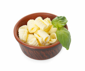 Tasty butter curls and basil leaves in bowl isolated on white