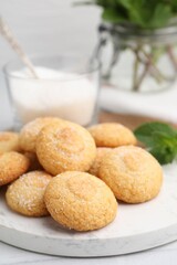 Tasty sweet sugar cookies, milk and mint on white table, closeup