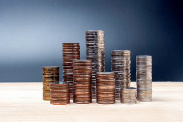 coins stacked on wooden with black background. Concept of saving money, economy, investment, growing business and wealth.