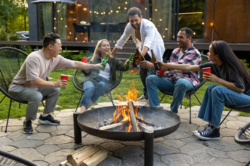 Multiethnic friends gathering together at garden near fire grill enjoying outdoor party