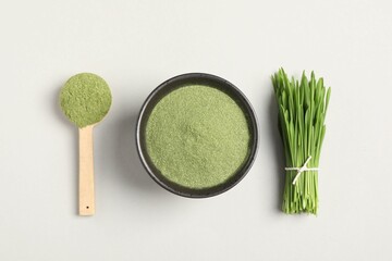Wheat grass powder and fresh green sprouts on light table, flat lay