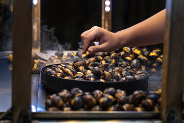 Close-up of the chestnut seller's hand roasting chestnuts outdoors on Istiklal Street - Powered by Adobe