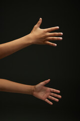 Children's hand gesturing, shows palms against black background. Two teen, African-American arms....