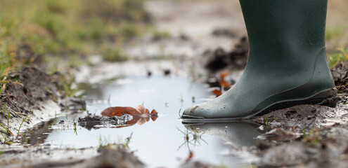 A foot in wellington submerged in puddle and mud. Zbliżenie, detal.