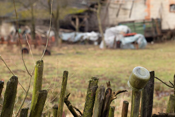 Wooden rails of an old fence, on one of them hung a jar, in the background a rural backyard, retro.