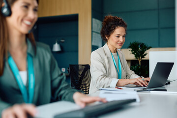 Obraz premium Smiling businesswoman working on laptop in office.