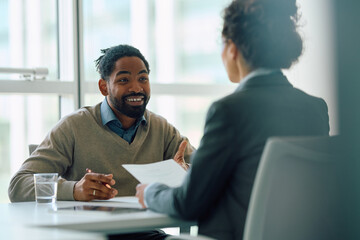 Happy black man having  meeting with insurance agent in office.