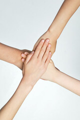 Close up of children putting their hands together against grey background. Friends with stack of hands showing unity and teamwork. Concept of youth, expression, beauty, emotions, gestures. Ad