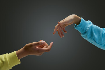 Cropped image of children's hands reaching to each other against gradient grey background. Helping...