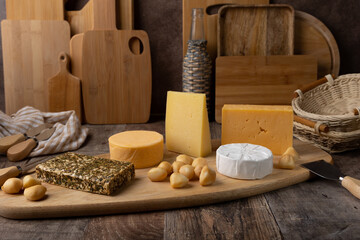 Cheese assorted on a wooden board, rustic style. Several varieties of whole cheese: parmesan,...