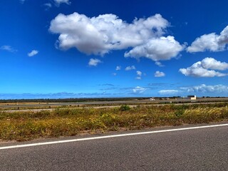 An asphalt road Country Side View with blue sky and wonderful white clouds
