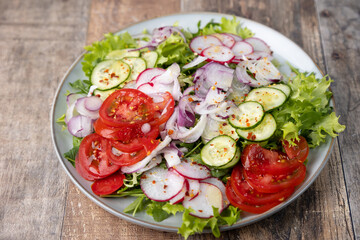 A plate of fresh chopped vegetables dressed with olive oil and spices. Vegetarian dish. Fresh vegetable salad in rustic style. Selective focus, close-up.