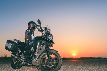 バイクで夕焼けを眺めるライダー
