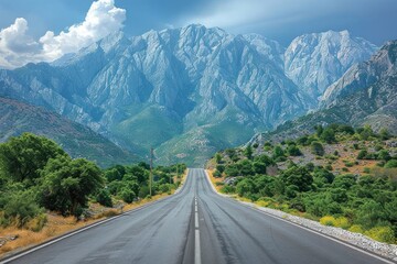 Naklejka premium Scene of a road stretching into the distance, framed by towering mountains