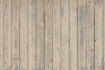 An old fence with peeling paint, a wall of light, wooden boards in the background of a rural house....