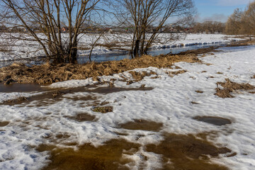 Early spring, melting snow, under the bright rays of the sun, thawed patches in the snow, colorful winter landscape
