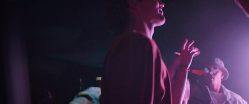 Young adult man smiles at a music festival while dancing to music