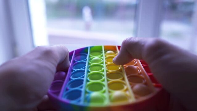 Close-up of man fingers playing pop it, having fun with popular fidget toy