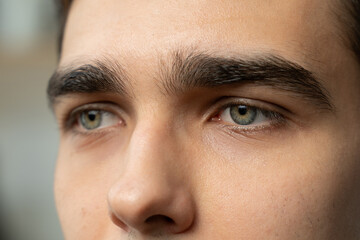 A close-up captures the detailed nuances of a mans green eyes, reflecting a subtle intensity and...