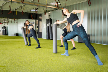 A group of 3 adult women are playing sports in a gym room.The girls perform a lateral position with...