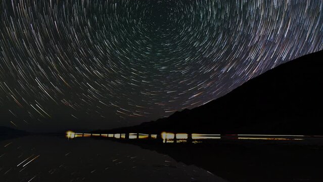 Timelapse night to day transition of star trails reflected in ancient Lake Manly at Badwater Basin in Death Valley National Park in California, USA
