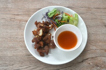 fried crispy pork bone or rib with fresh vegetable on plate dipping chili sauce cup 