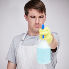 Man, portrait and studio for cleaning with spray bottle, serious and disinfectant liquid cleaner...
