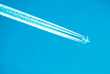 An airplane with four clear lines of contrails against a cloudless sky, the grace of flight. Travel...