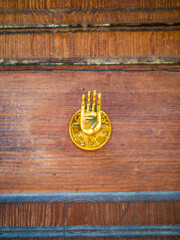 Old brass doorknob shaped as Abhayamudra gesture, symbolizing fearlessness and reassurance, outstretched hand beckoning viewers with good intentions, inviting strangers, evoking peace and protection.